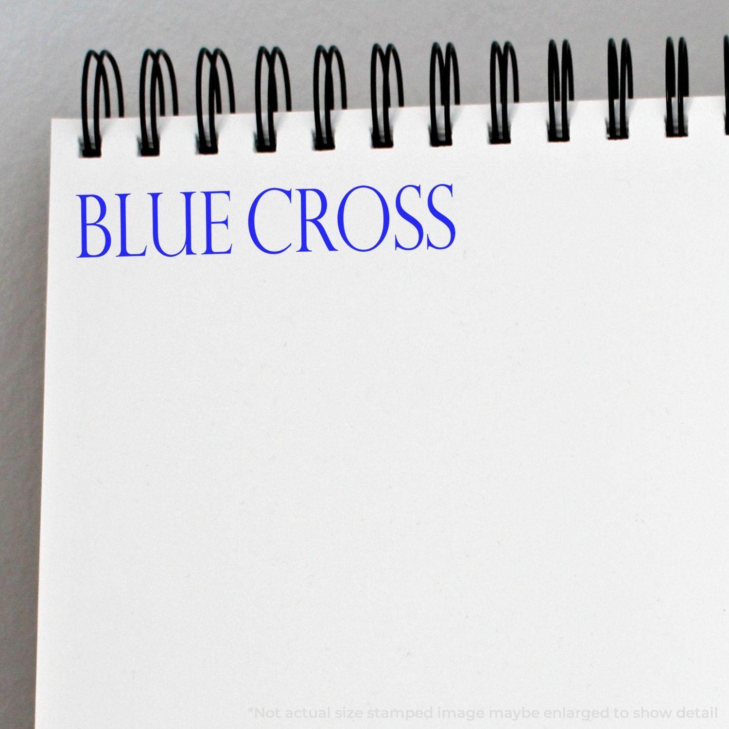 Large Blue Cross Rubber Stamp imprint on a white spiral notebook, showcasing the clear and bold blue text BLUE CROSS at the top left corner.