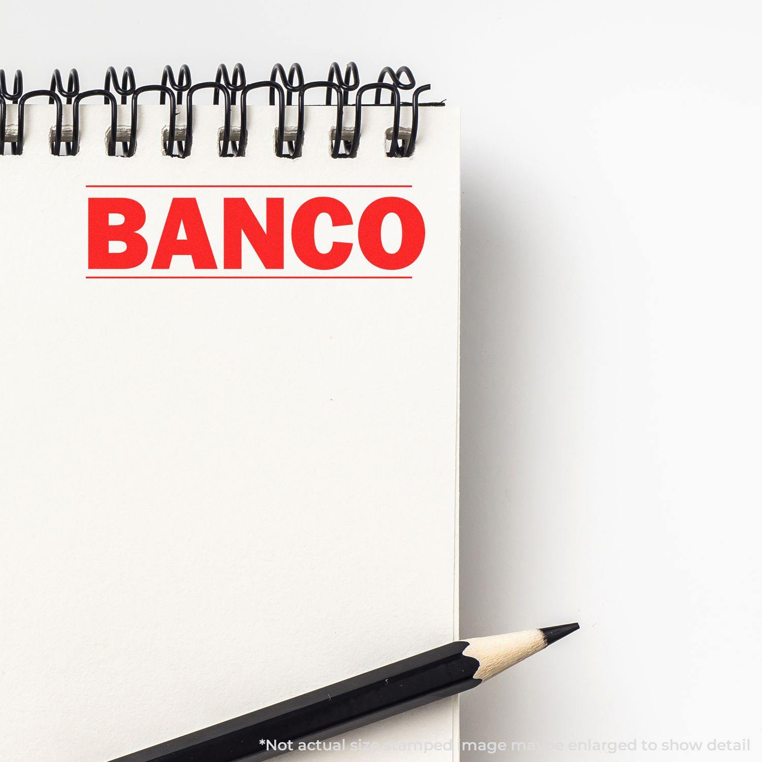 Bold Banco Rubber Stamp impression on a white notepad with a black pencil placed diagonally at the bottom right.