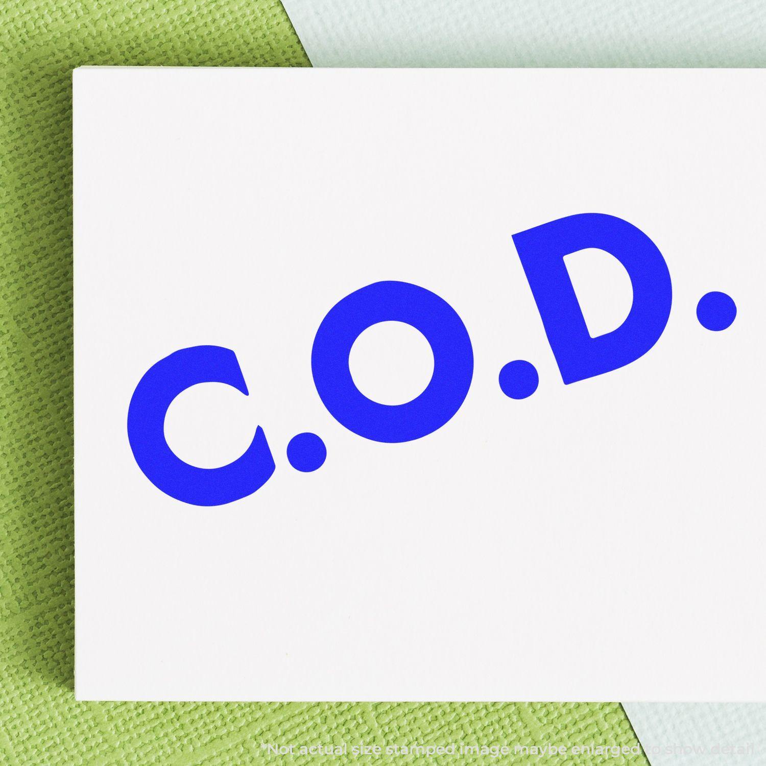 Large Pre-Inked Bold COD Stamp in blue ink on white paper, placed on a green and white textured background.