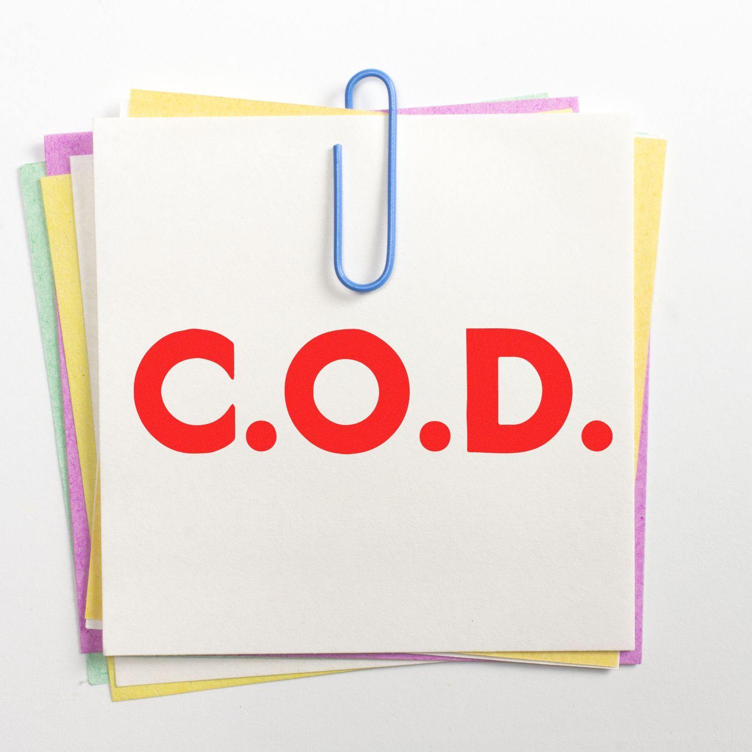 Large Pre-Inked Bold COD Stamp imprint on a stack of colorful sticky notes held together by a blue paperclip.