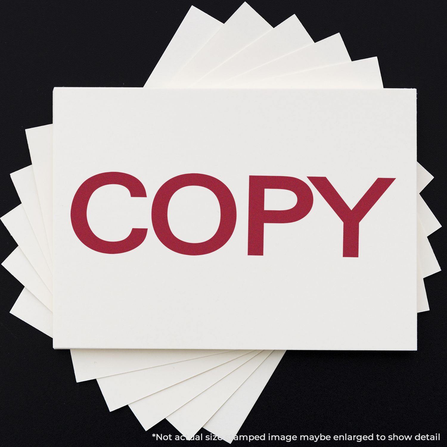 Large Bold Copy Rubber Stamp used to imprint the word COPY in red ink on a white card, displayed on a black background.