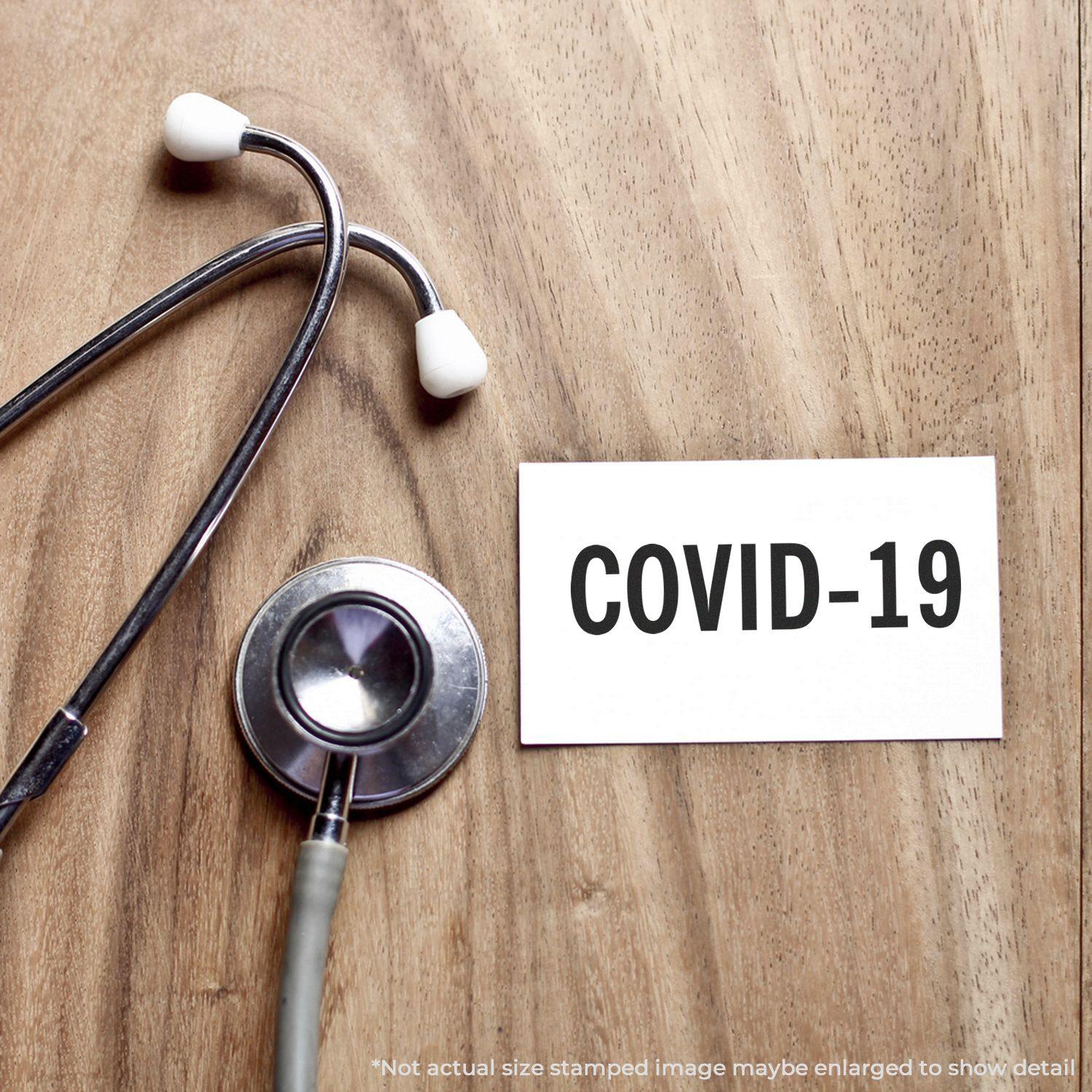 Stethoscope and card stamped with COVID-19 using the Large Pre-Inked Bold Covid-19 Stamp on a wooden surface.