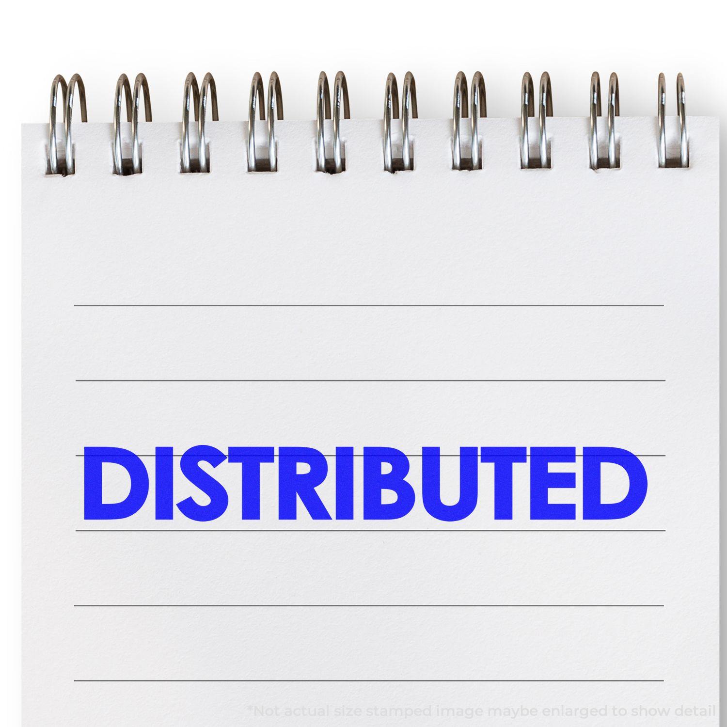 Large Bold Distributed Rubber Stamp imprint in blue ink on a white notepad with spiral binding, showing the word DISTRIBUTED in bold letters.