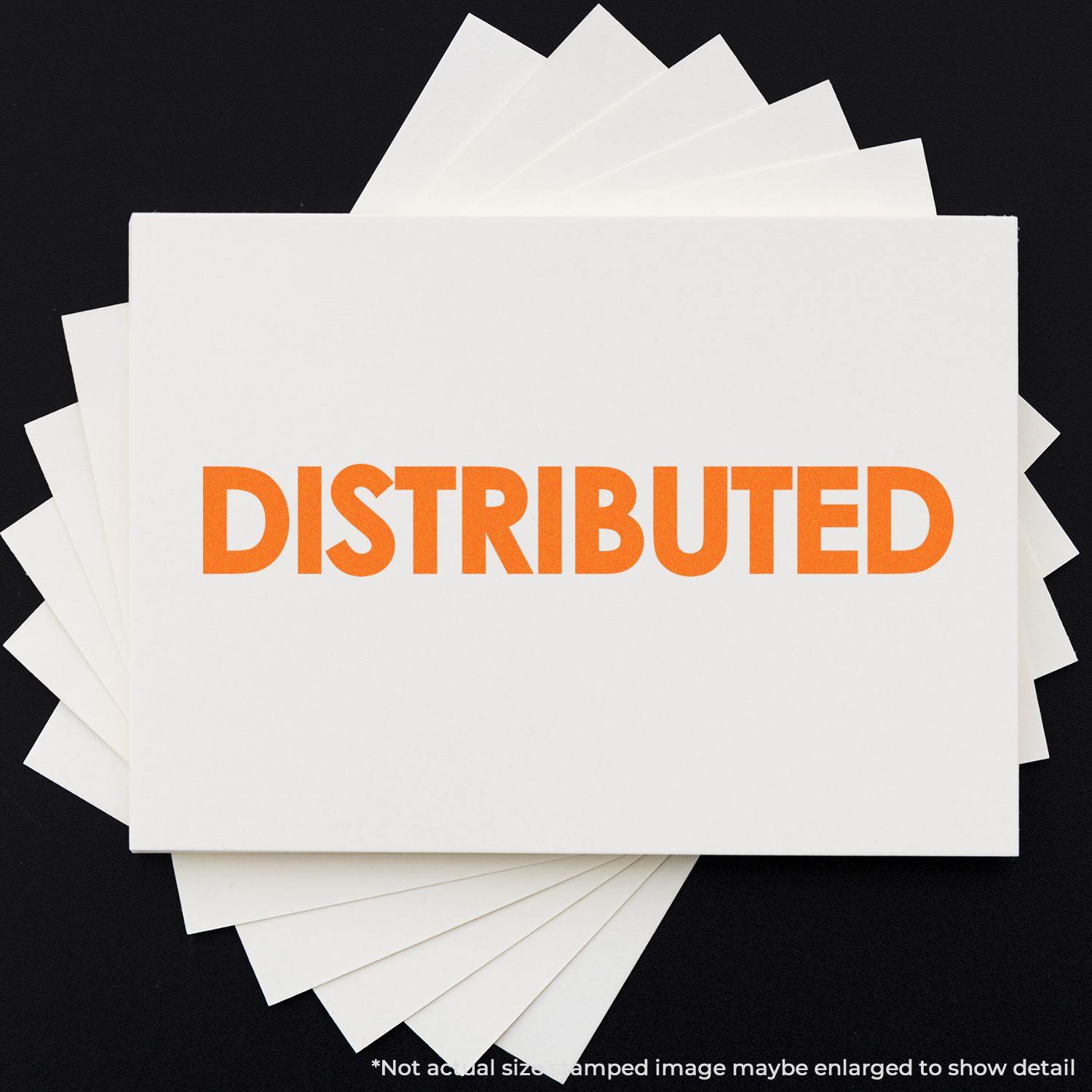 Large Bold Distributed Rubber Stamp in use, showing the word DISTRIBUTED in bright orange on a white card, with multiple cards underneath.