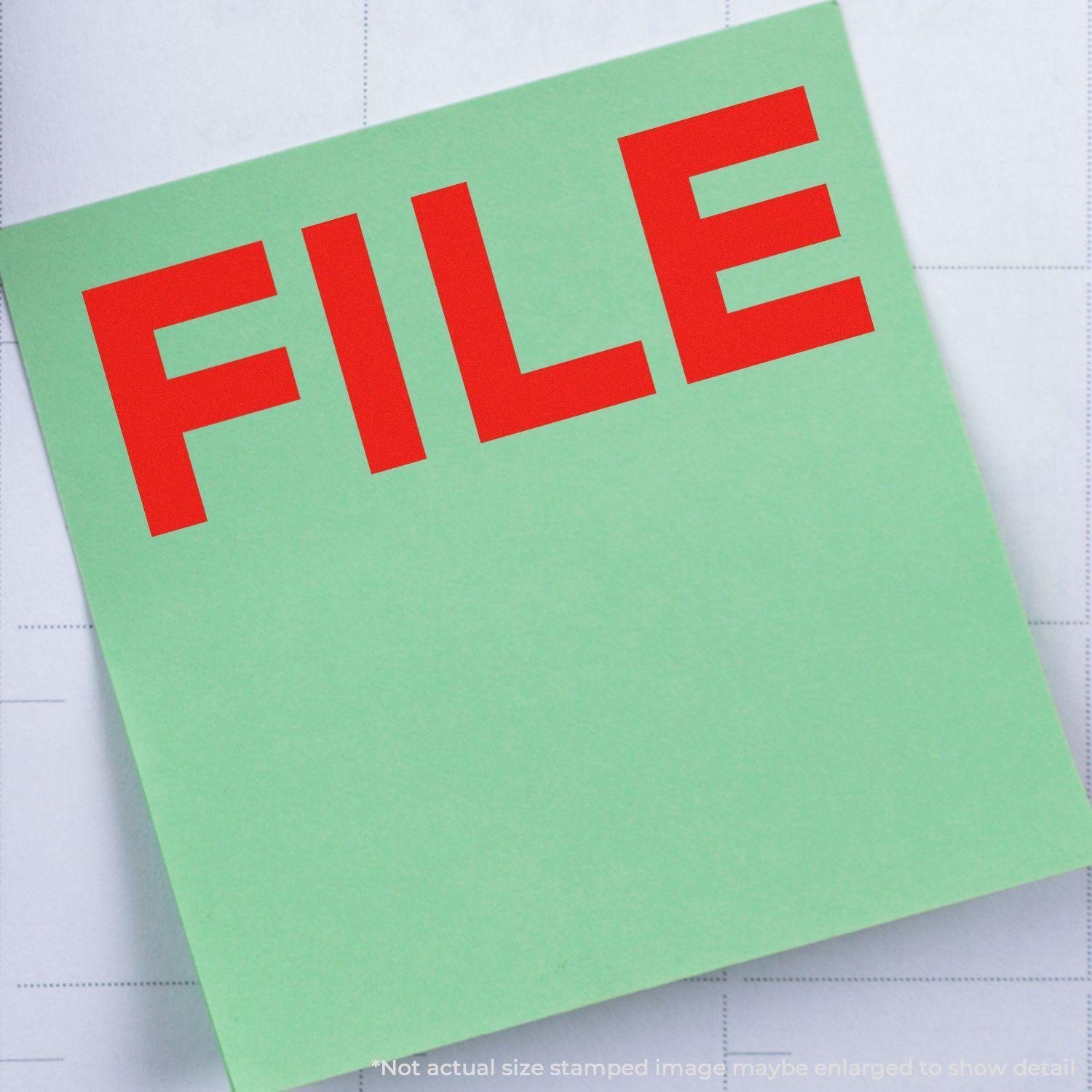 Green paper stamped with a red FILE using a Bold File Rubber Stamp, placed on a grid-patterned background.