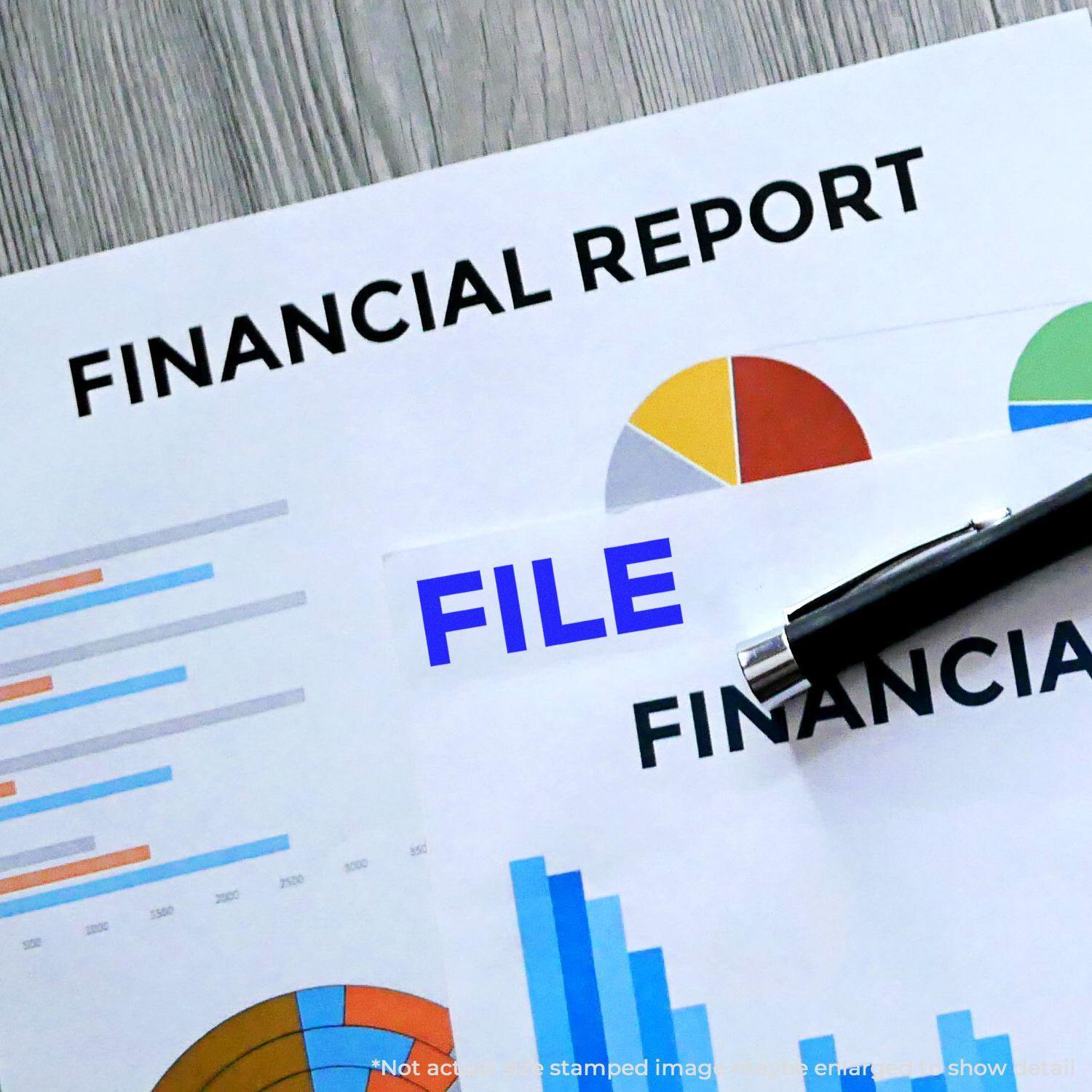 Financial reports with charts and graphs, a pen, and a Bold File Rubber Stamp marking FILE in blue on one document.