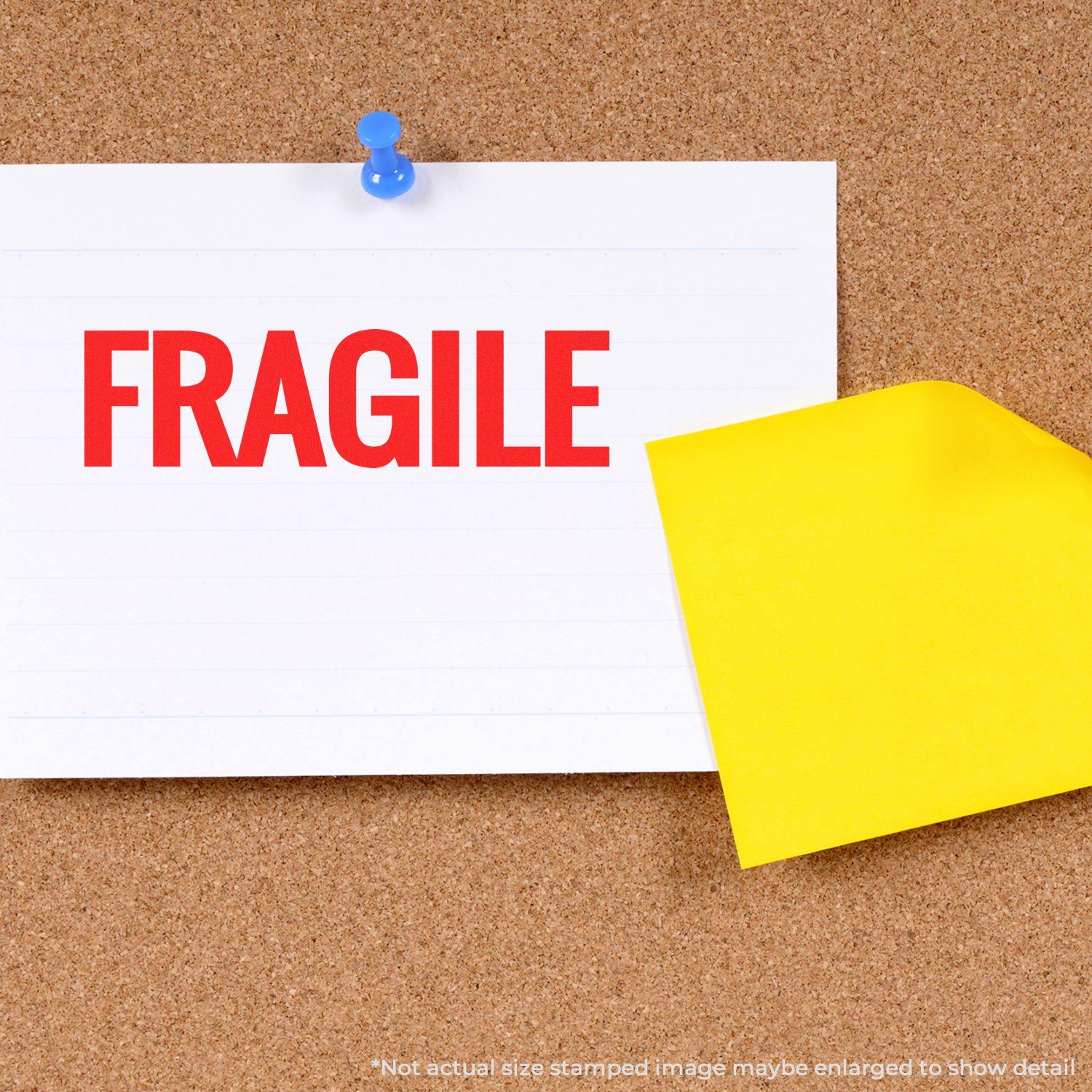 Self Inking Bold Fragile Stamp used on a white paper pinned to a corkboard, with a yellow sticky note partially visible.