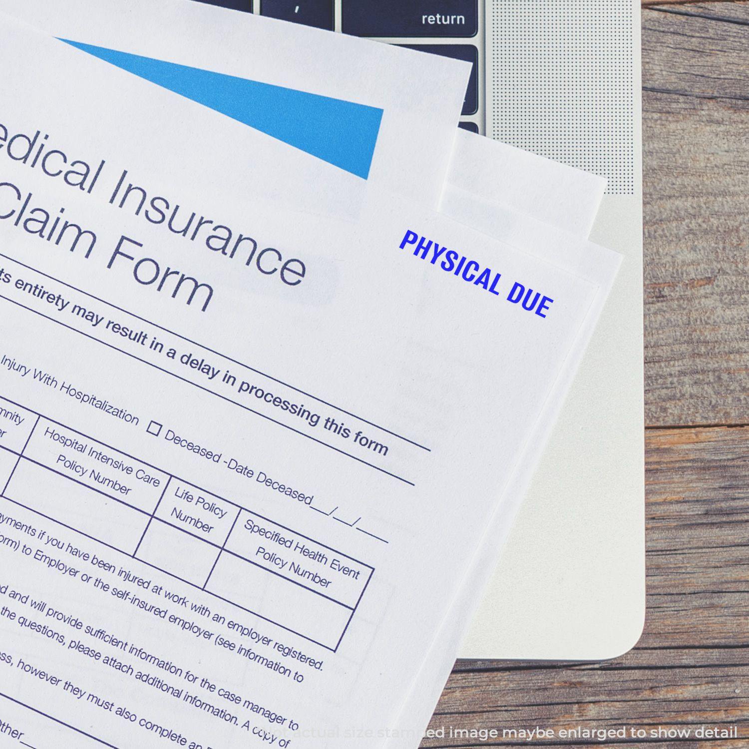 Medical insurance claim form stamped with PHYSICAL DUE using the Bold Physical Due Rubber Stamp, placed on a laptop keyboard.