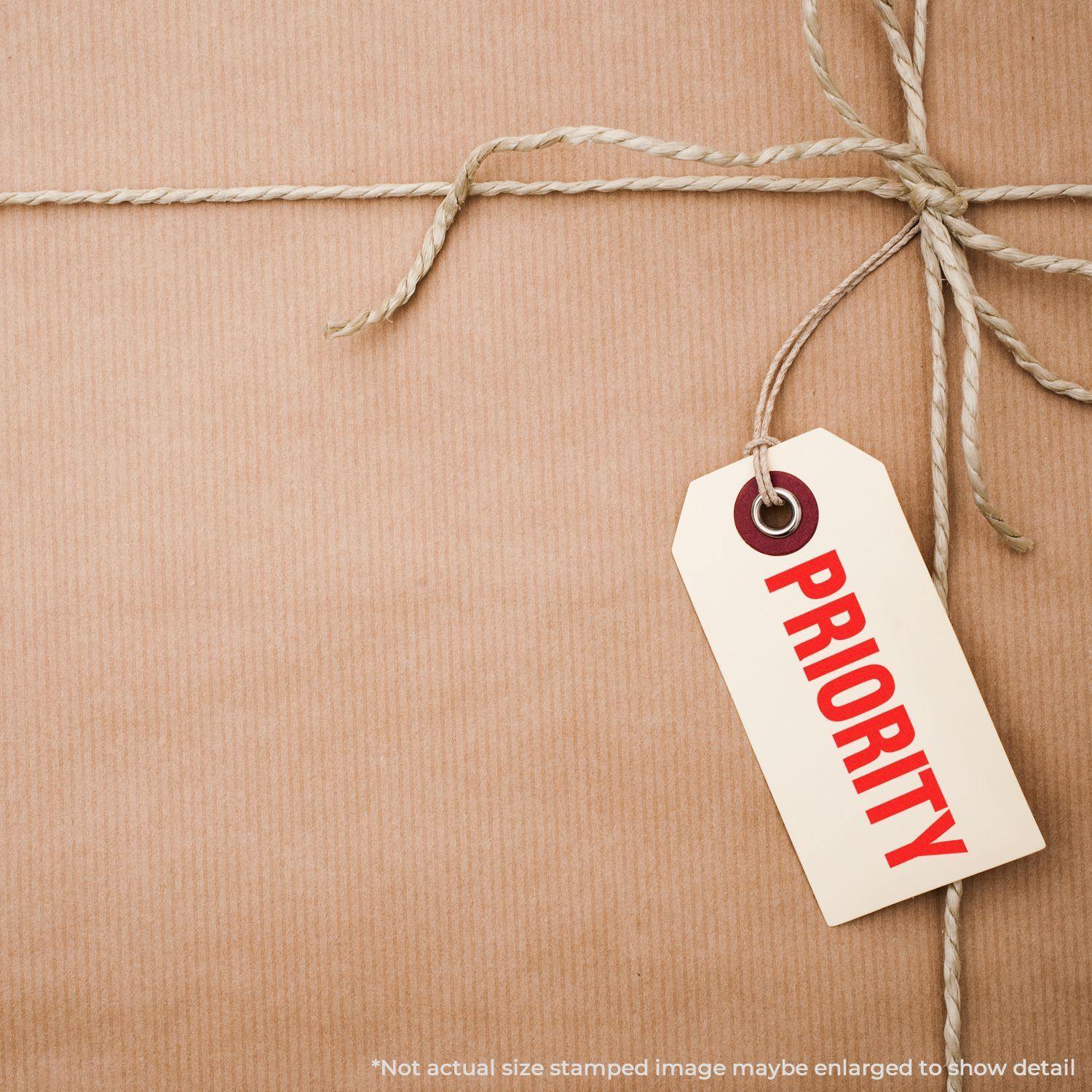 A brown paper package tied with string and a tag stamped PRIORITY using the Large Pre-Inked Bold Priority Stamp.