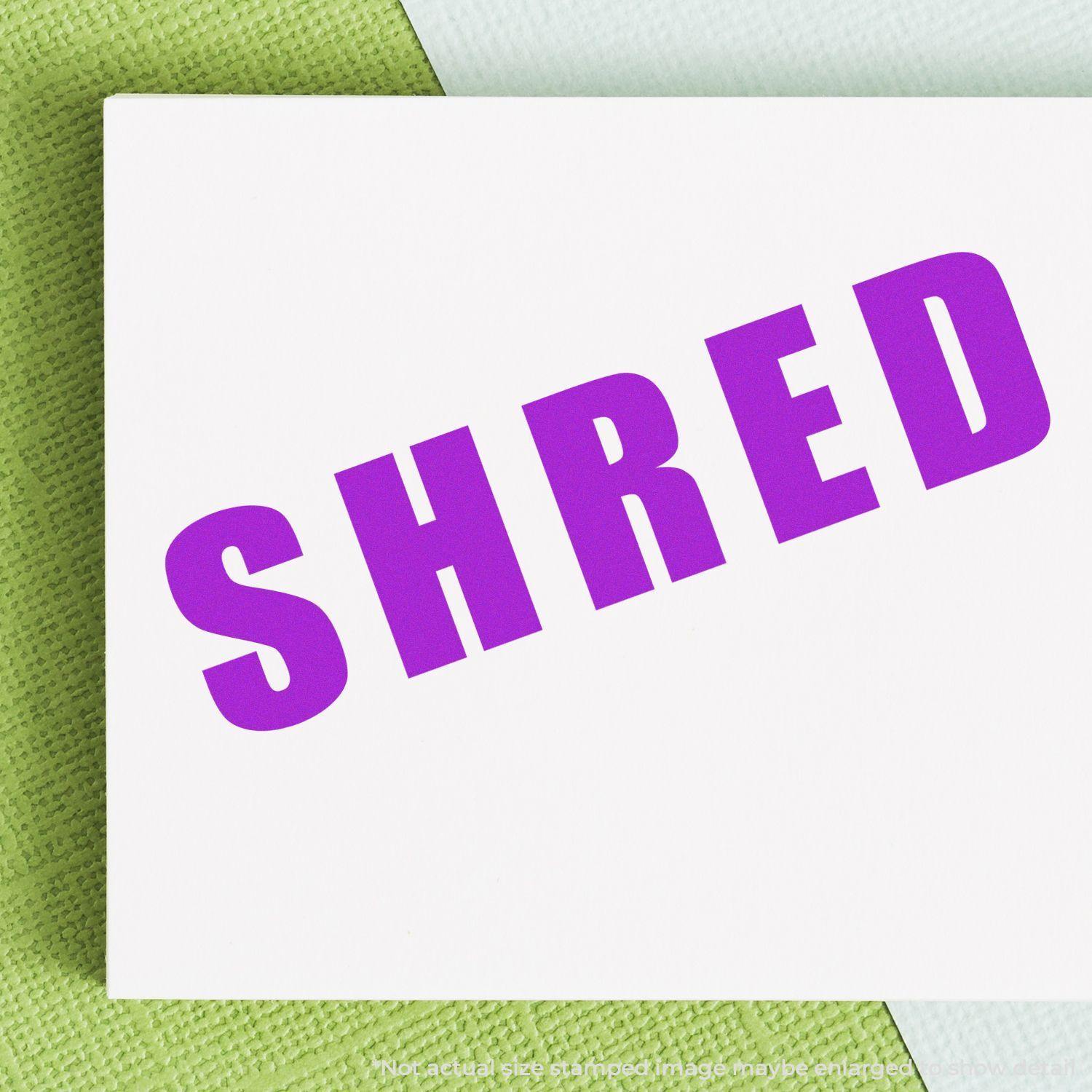 Bold Shred Rubber Stamp in purple ink on white paper, placed on a green textured surface.