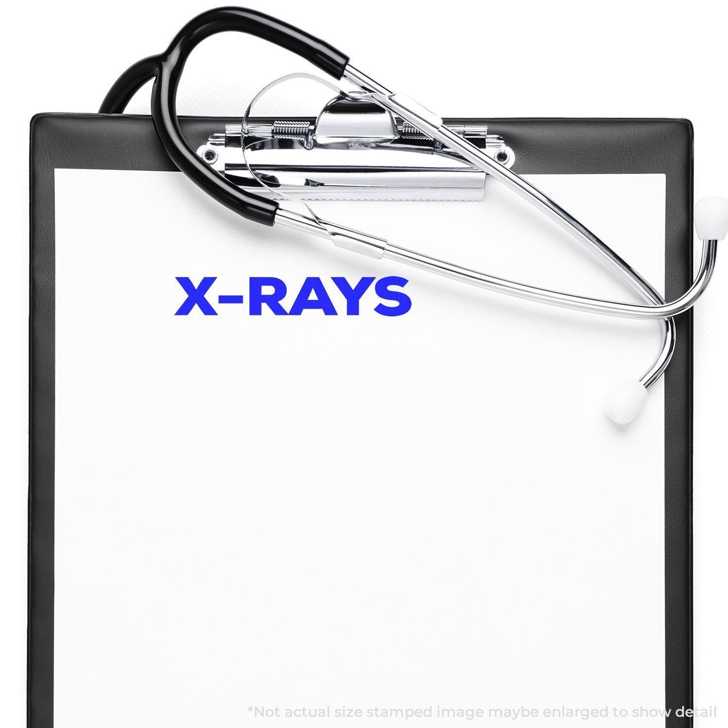 Clipboard with stethoscope and Large Self Inking Bold X-Rays Stamp marking X-RAYS in blue on paper.