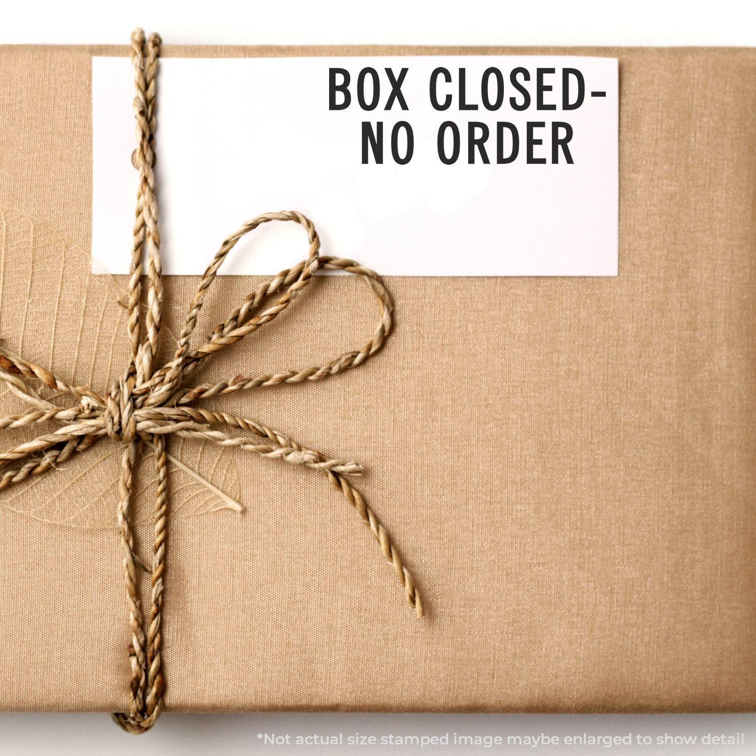 A Large Box Closed No Order Rubber Stamp is used on a brown wrapped package tied with twine, displaying the text BOX CLOSED - NO ORDER.