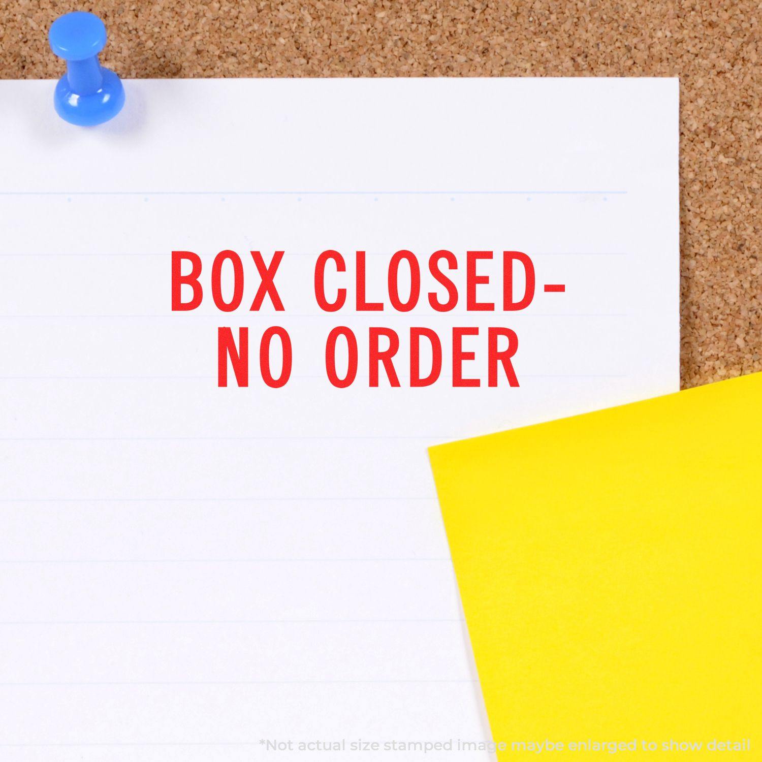 Large Box Closed No Order Rubber Stamp impression on white paper pinned to a corkboard, with a yellow paper beside it.