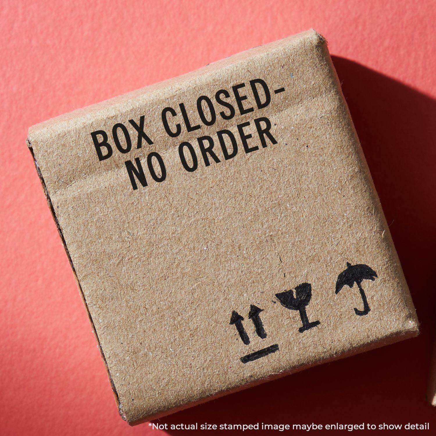 A cardboard box stamped with Box Closed - No Order using the Self Inking Box Closed No Order Stamp, on a red background.