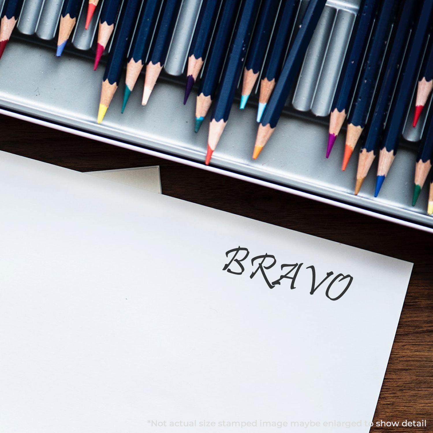 Bravo Rubber Stamp imprint on white paper, surrounded by colored pencils in a metal tray.