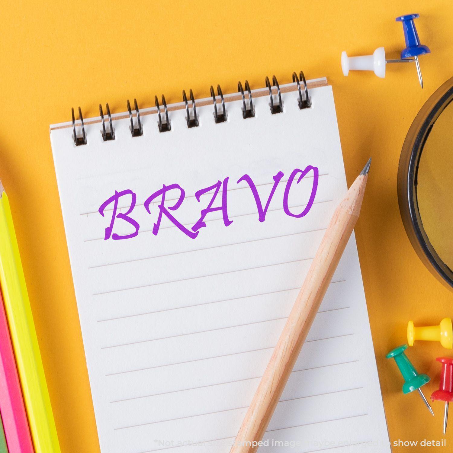 Bravo rubber stamp on a notepad with a pencil, colorful push pins, and a yellow background.