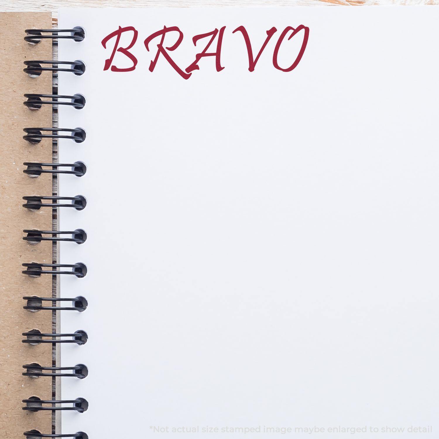 Bravo Rubber Stamp impression in red ink on a white page of a spiral-bound notebook with a brown cover.