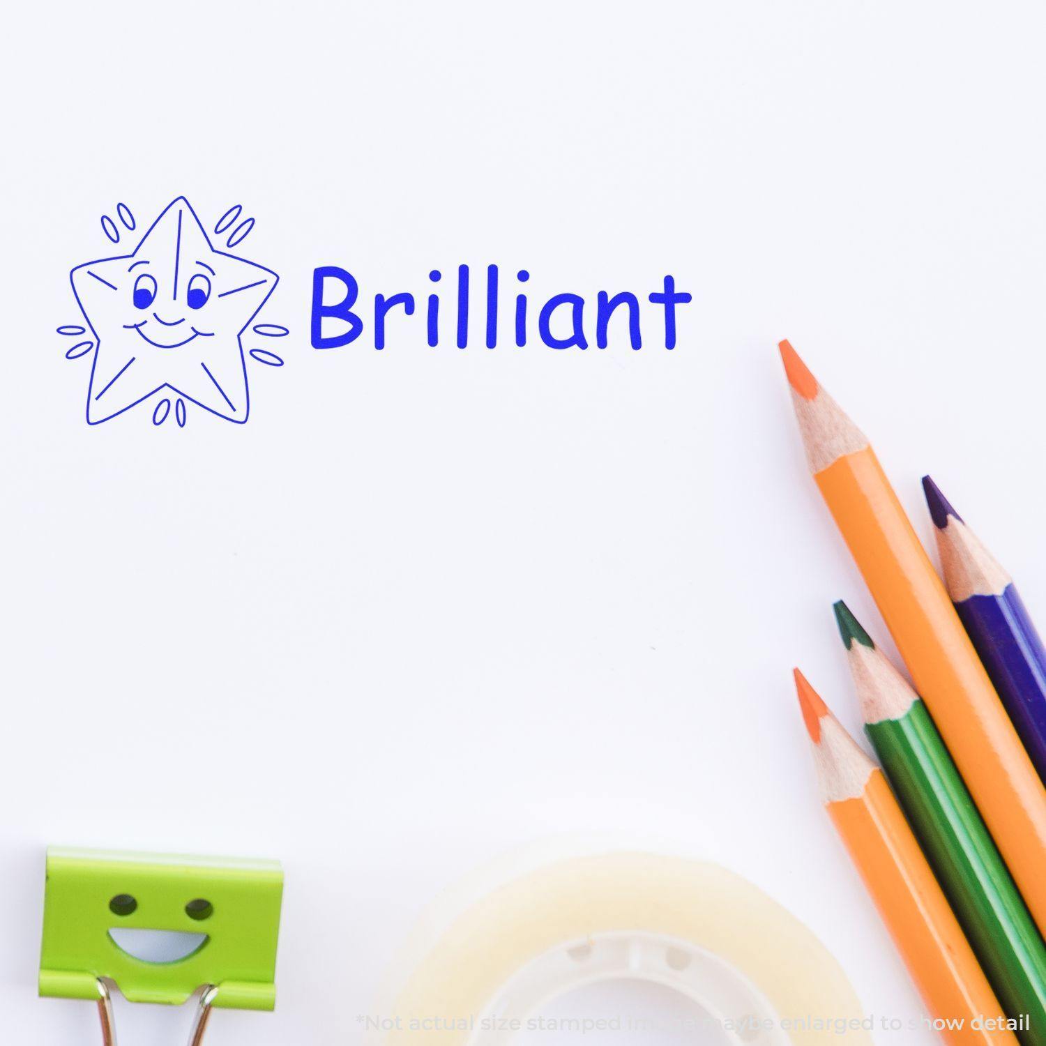 Self Inking Brilliant Stamp with a smiling star design stamped on paper, surrounded by colorful pencils, a green clip, and tape.