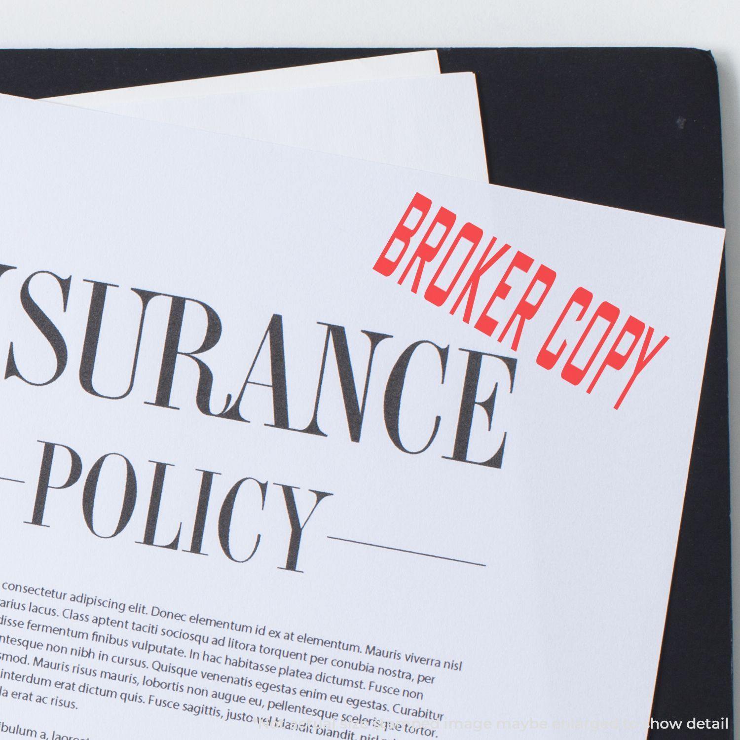 A Large Broker Copy Rubber Stamp marks BROKER COPY in red on an insurance policy document placed on a black folder.