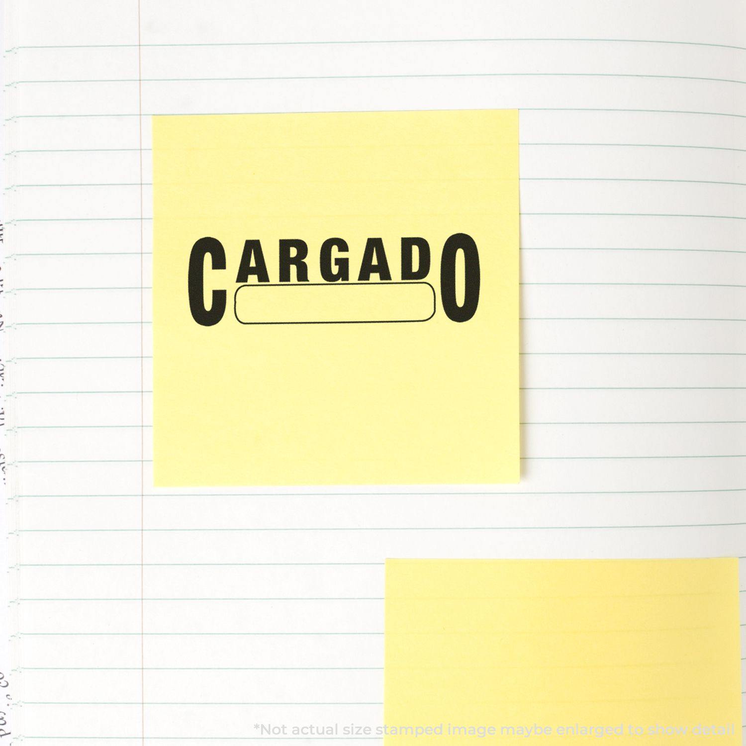 Yellow sticky note with CARGADO stamped in black ink using a rubber stamp, placed on a lined notebook page.