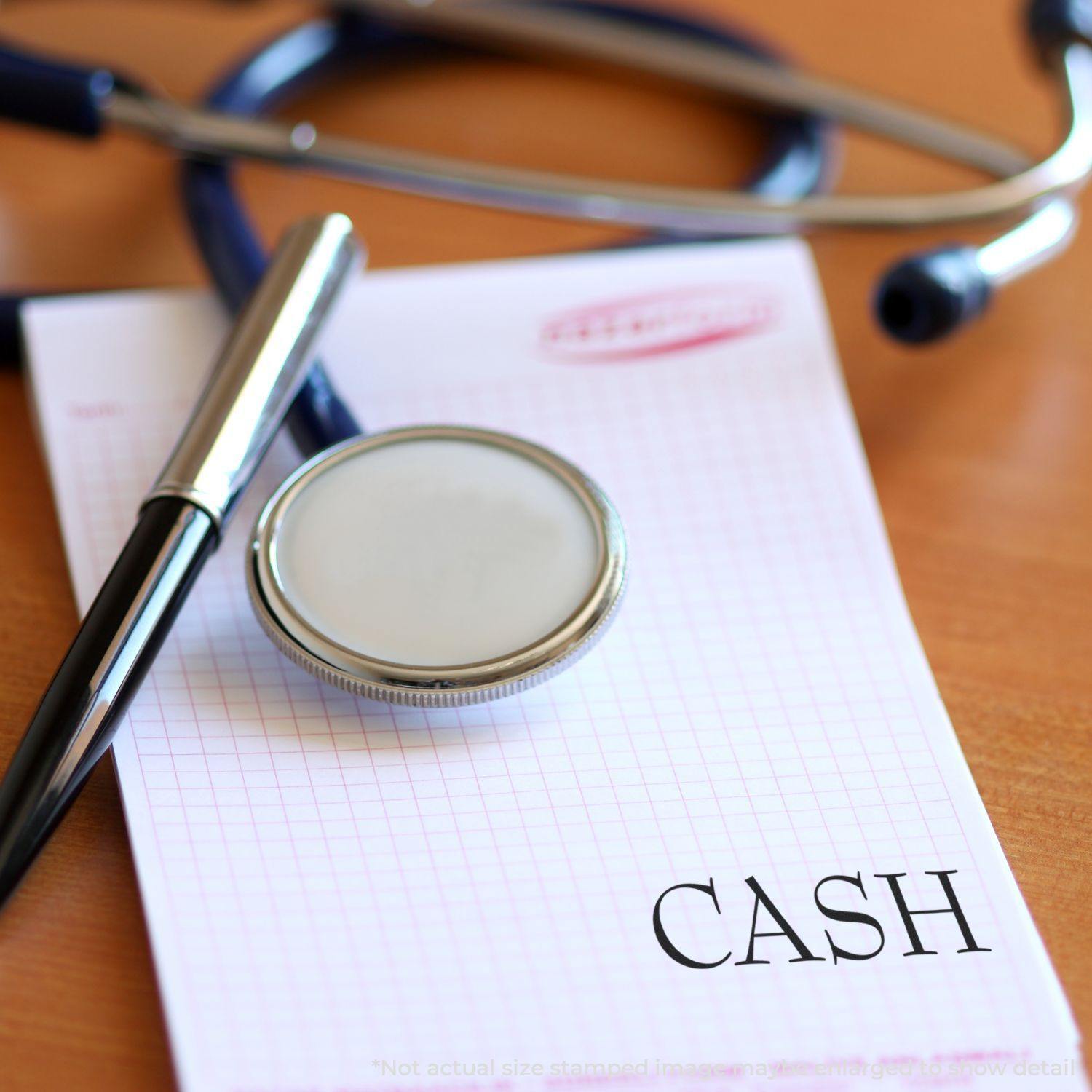 A stethoscope and pen on a notepad stamped with CASH using the Large Cash Rubber Stamp.