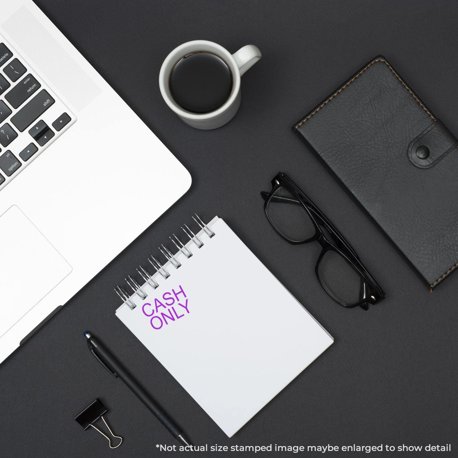 Large Pre-Inked Cash Only Stamp used on a notepad, placed on a desk with a laptop, coffee cup, glasses, wallet, and paper clip.