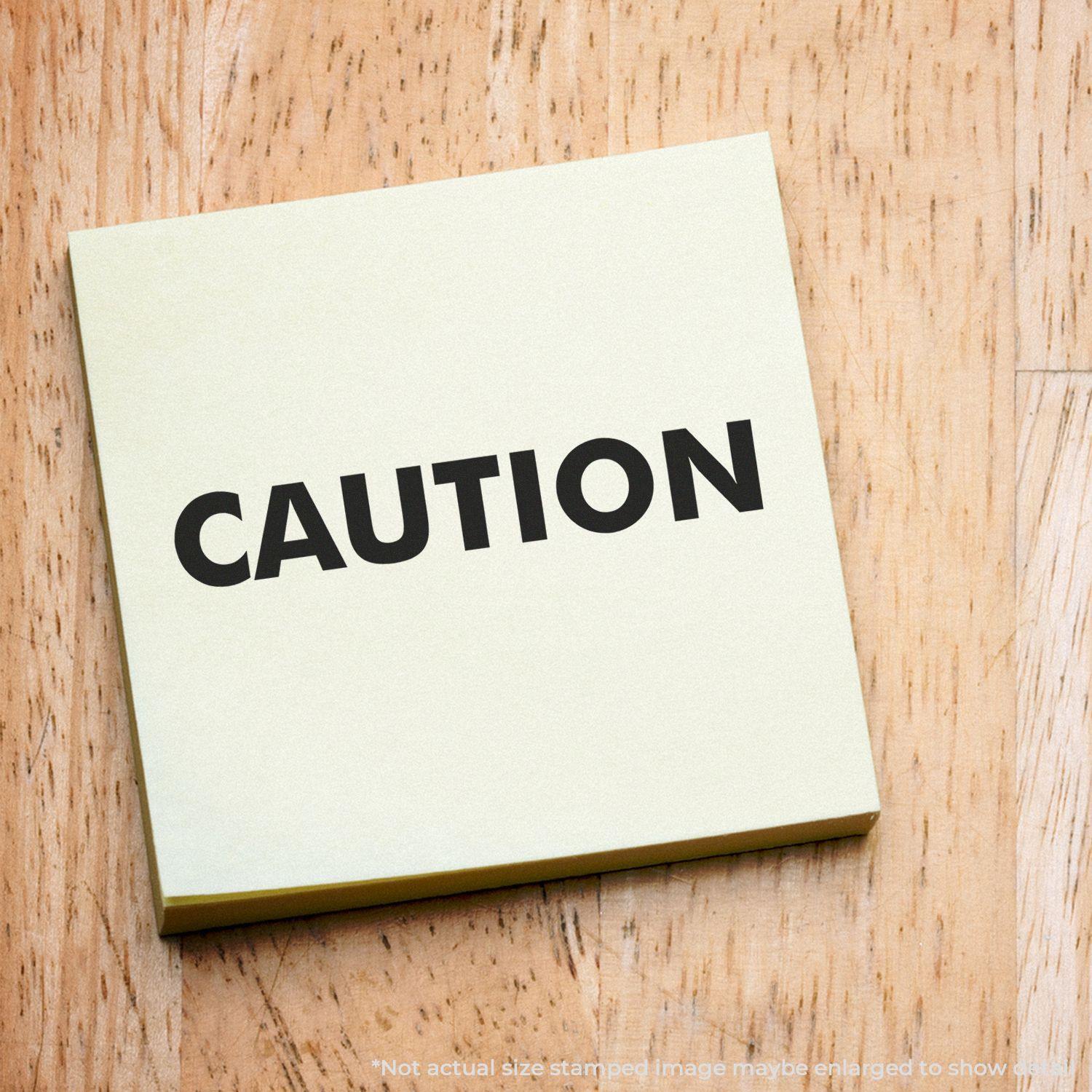 Self Inking Caution Stamp on a yellow sticky note placed on a wooden surface.