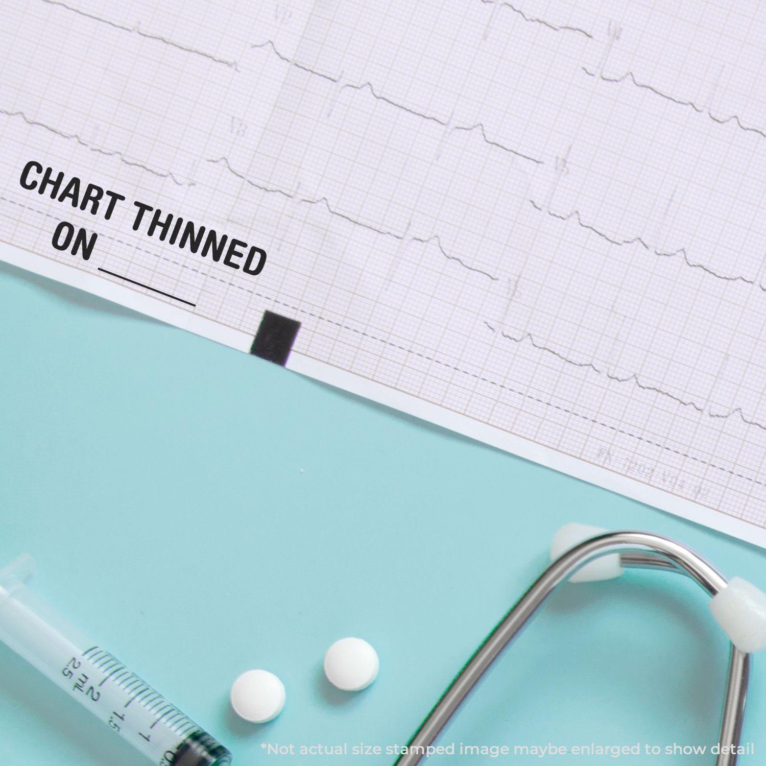 Large Pre-Inked Chart Thinned On Stamp used on a medical chart, with a syringe, pills, and stethoscope on a light blue surface.