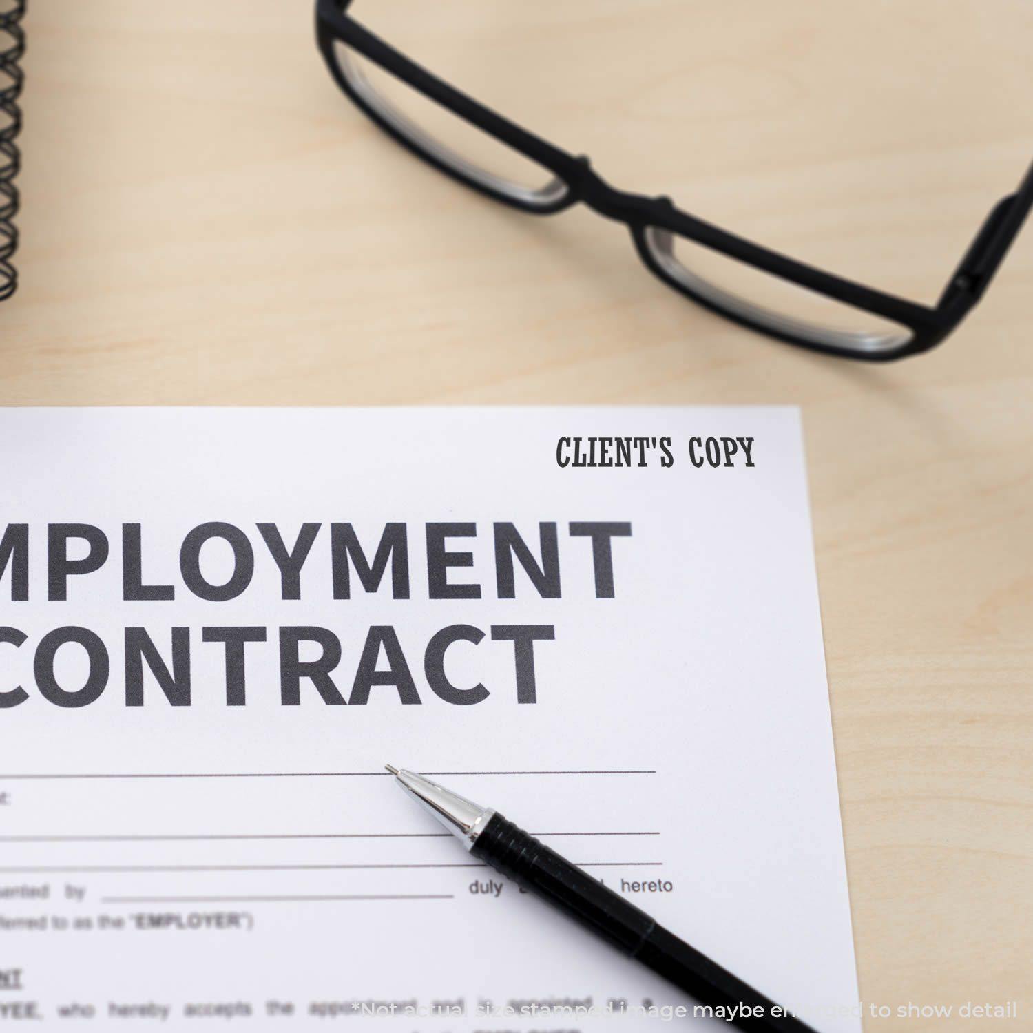 Large Pre-Inked Clients Copy Stamp marking CLIENT'S COPY on an employment contract, with glasses and a pen on a wooden desk.