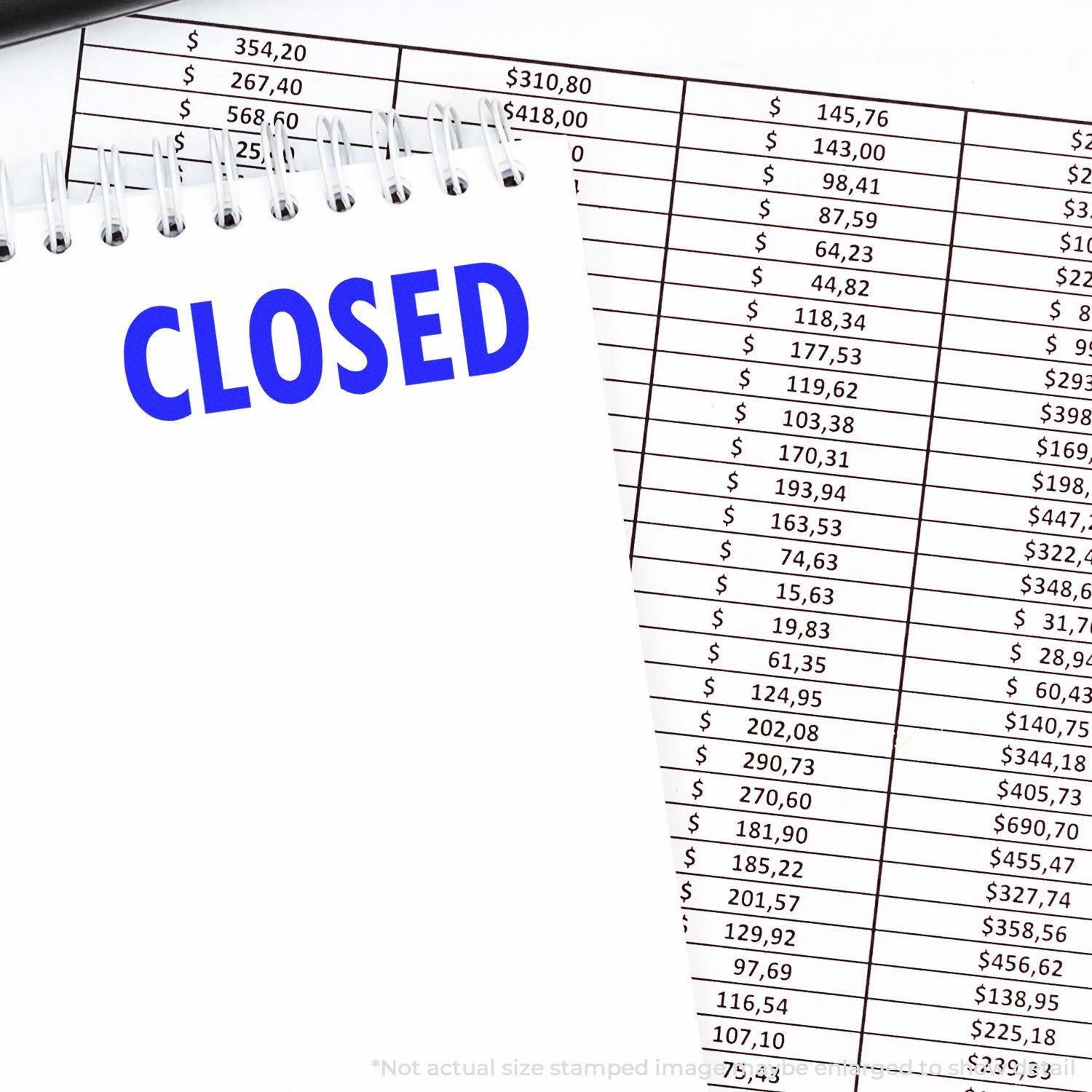 Large Pre-Inked Closed Stamp used on a white notepad with CLOSED in blue ink, placed on top of financial documents.