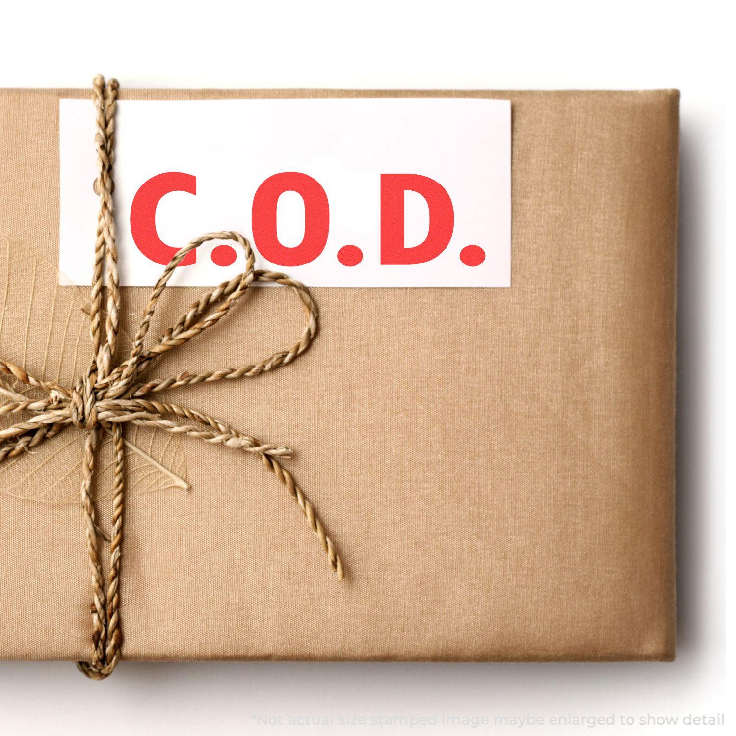 A brown package tied with twine, featuring a white label stamped with C.O.D. in red using the COD Rubber Stamp.