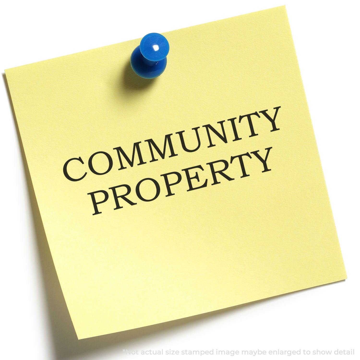 Yellow sticky note with COMMUNITY PROPERTY stamped on it using the Community Property Rubber Stamp, pinned with a blue pushpin.