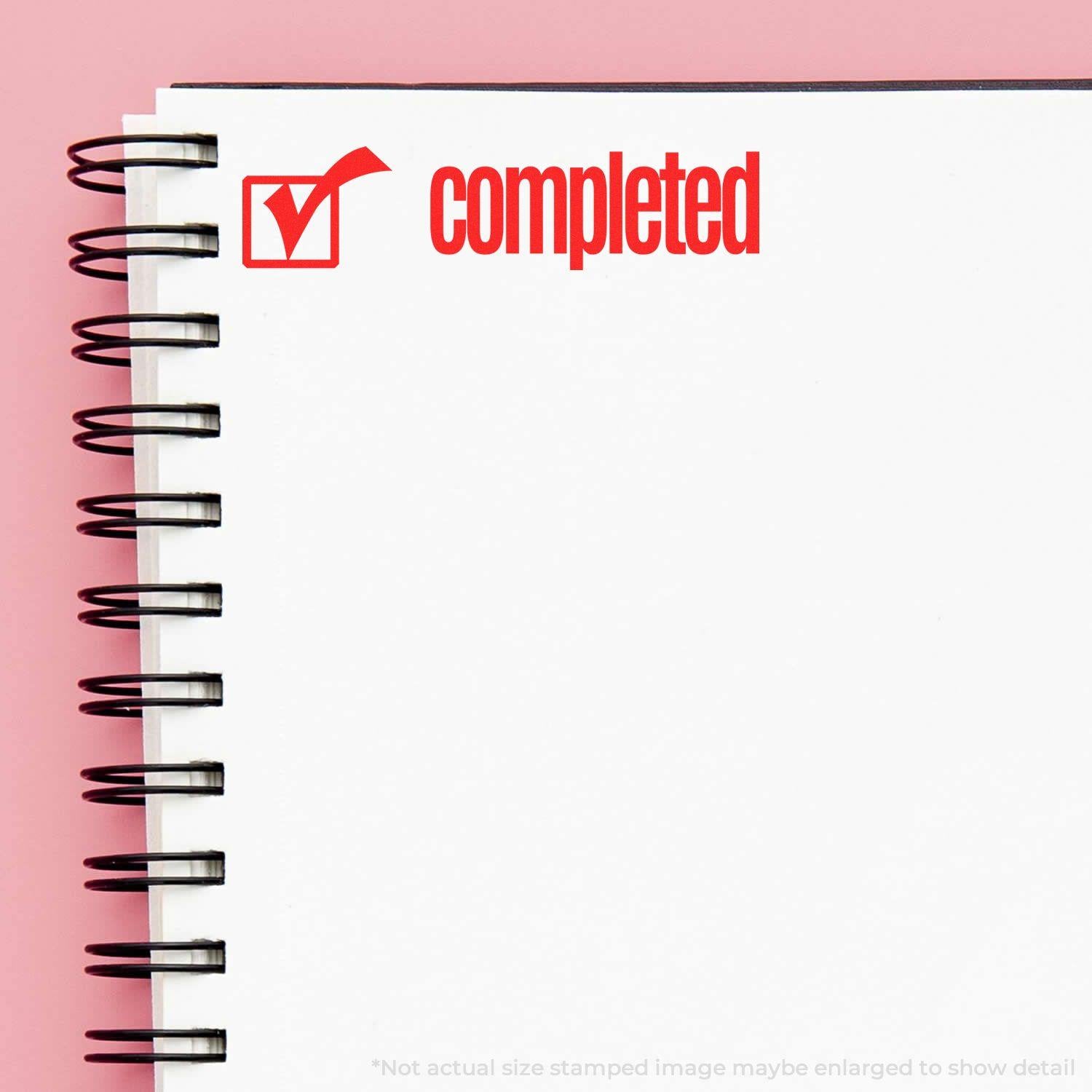 Spiral notebook with a red Completed with Checkbox Rubber Stamp mark on the top right corner against a pink background.