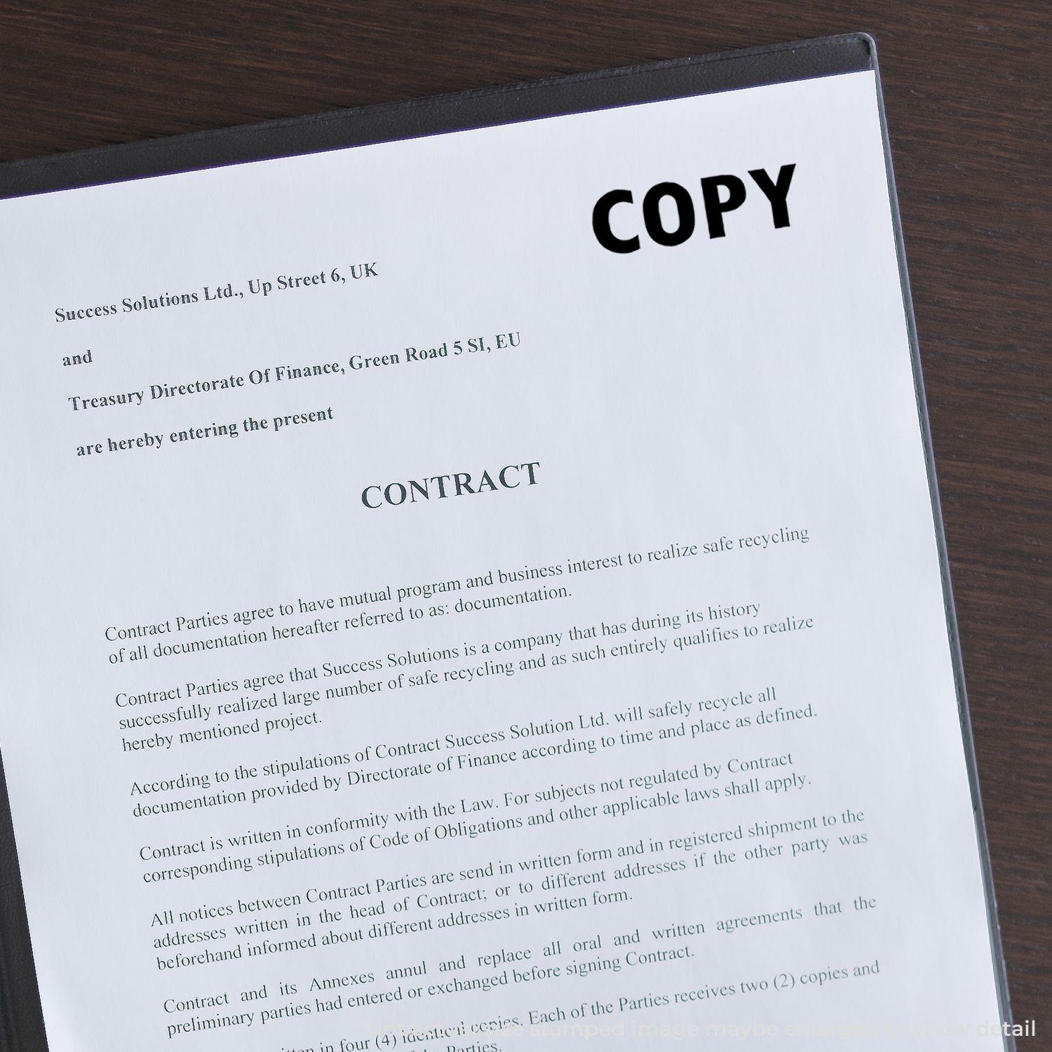 A Large Copy Rubber Stamp is used to mark the word COPY on a contract document placed on a dark wooden surface.