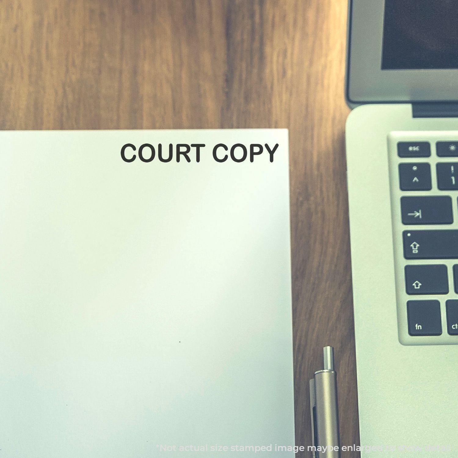 Large Court Copy Rubber Stamp used on a white paper next to a laptop and pen on a wooden desk.