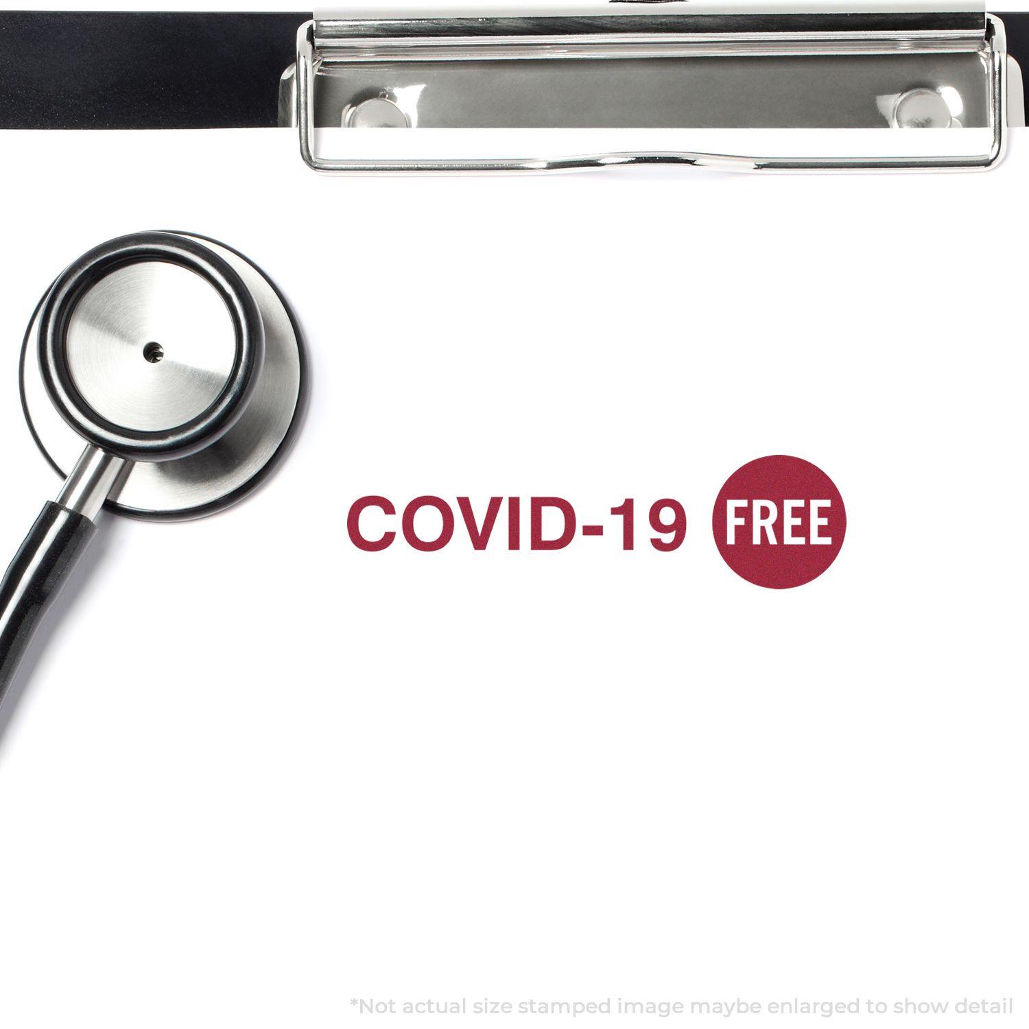 A stethoscope and a clipboard with a paper stamped COVID-19 FREE using the Covid-19 Rubber Stamp.