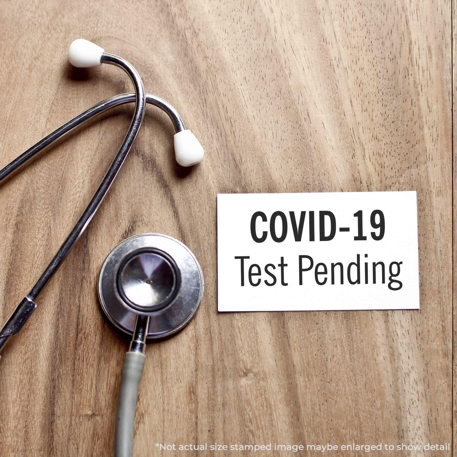 Covid-19 Test Pending Rubber Stamp on a wooden surface next to a stethoscope, indicating a pending test status.