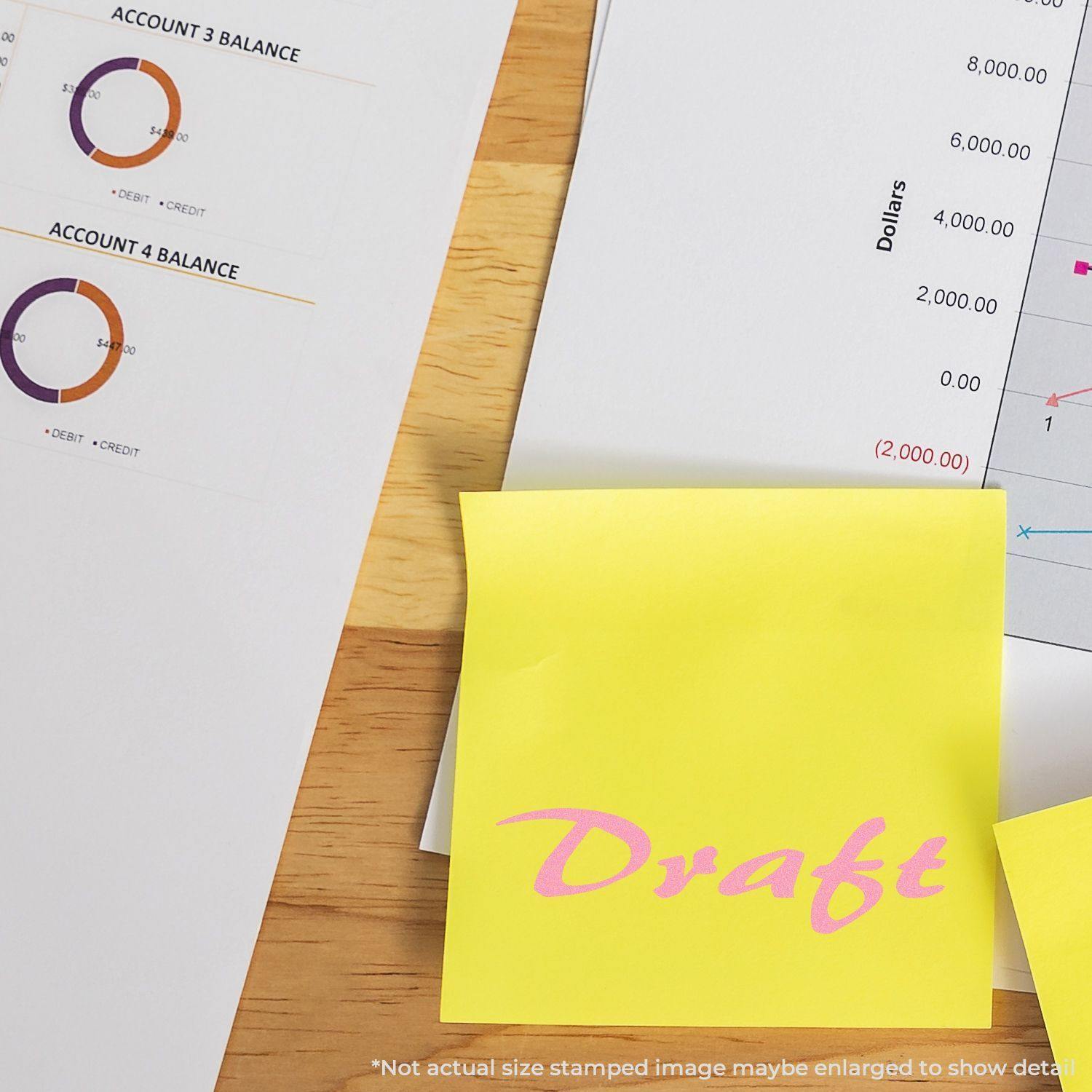 Large Self Inking Cursive Draft Stamp used on a yellow sticky note, placed on a wooden desk with financial documents in the background.