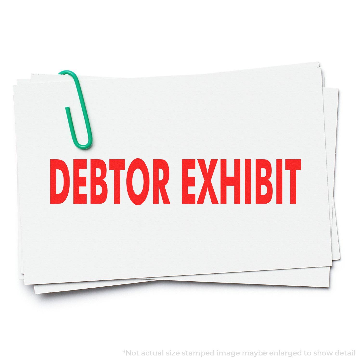 Stack of papers stamped with DEBTOR EXHIBIT in red ink, using the Large Self Inking Debtor Exhibit Stamp, secured with a green paperclip.