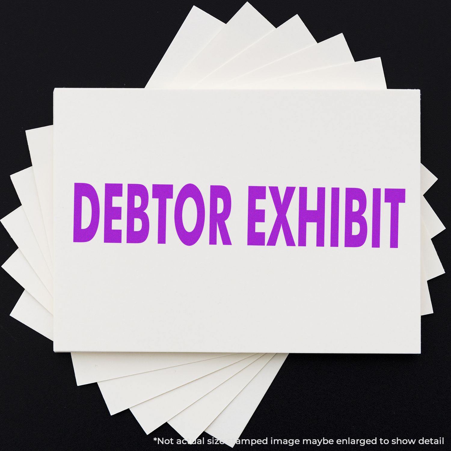 Debtor Exhibit Rubber Stamp in use, displaying bold purple text DEBTOR EXHIBIT on a white card, with multiple cards underneath.