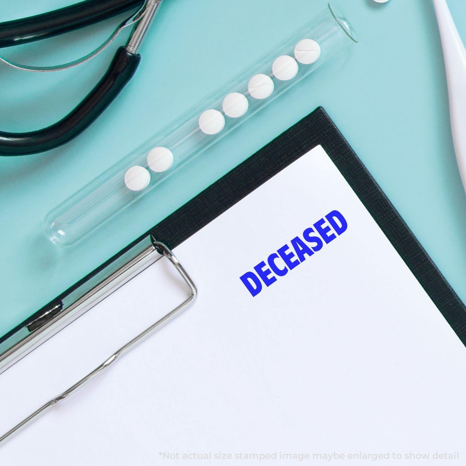 Clipboard with DECEASED stamped in blue using the Large Deceased Rubber Stamp, next to a stethoscope and a test tube with pills.