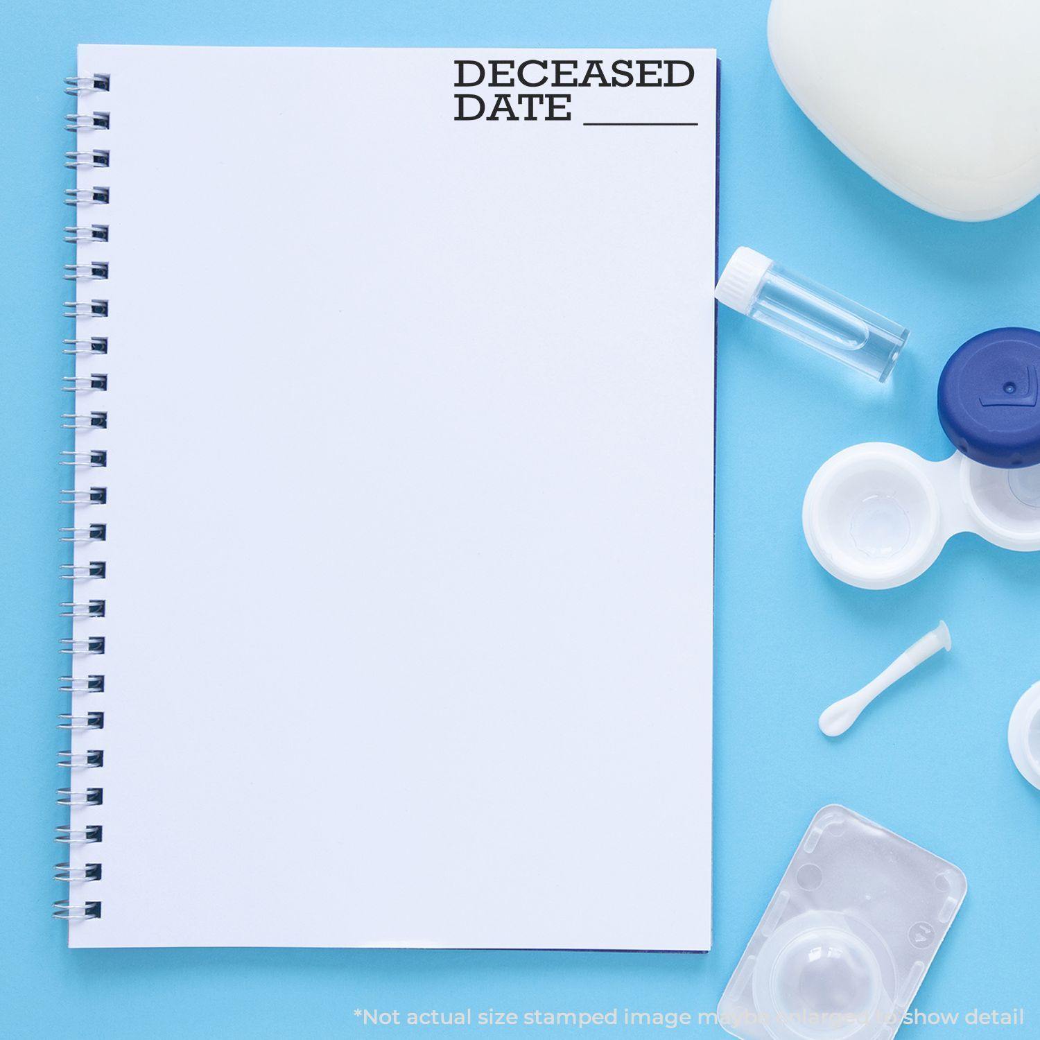 Large Deceased Date Rubber Stamp used on a blank spiral notebook, surrounded by various office and medical supplies on a blue background.