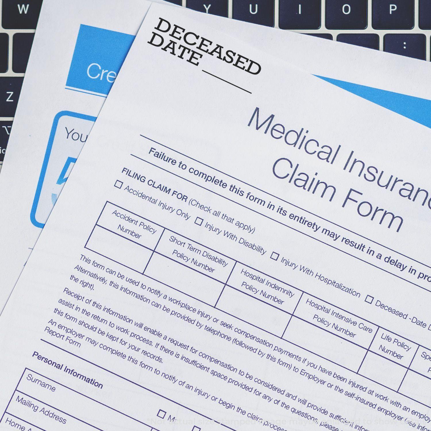 Medical insurance claim form stamped with Deceased Date using the Large Pre-Inked Deceased Date Stamp, placed on a laptop keyboard.