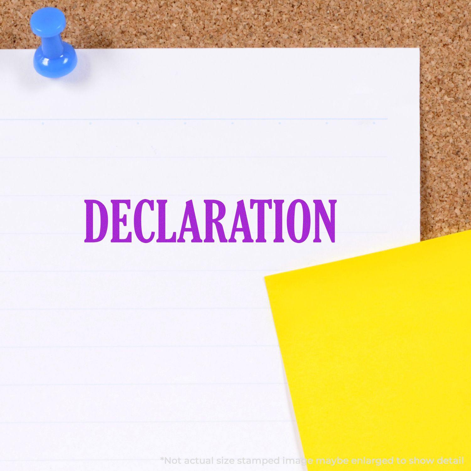 A white paper with the word DECLARATION stamped in purple using the Declaration Rubber Stamp, pinned to a corkboard with a blue pushpin.