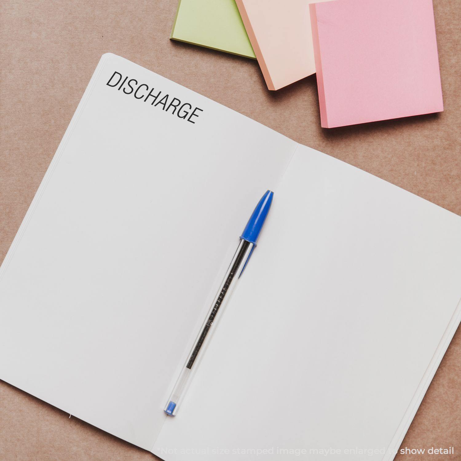 Open notebook with DISCHARGE stamped using Discharge Rubber Stamp, blue pen placed on the page, and colorful sticky notes in the background.