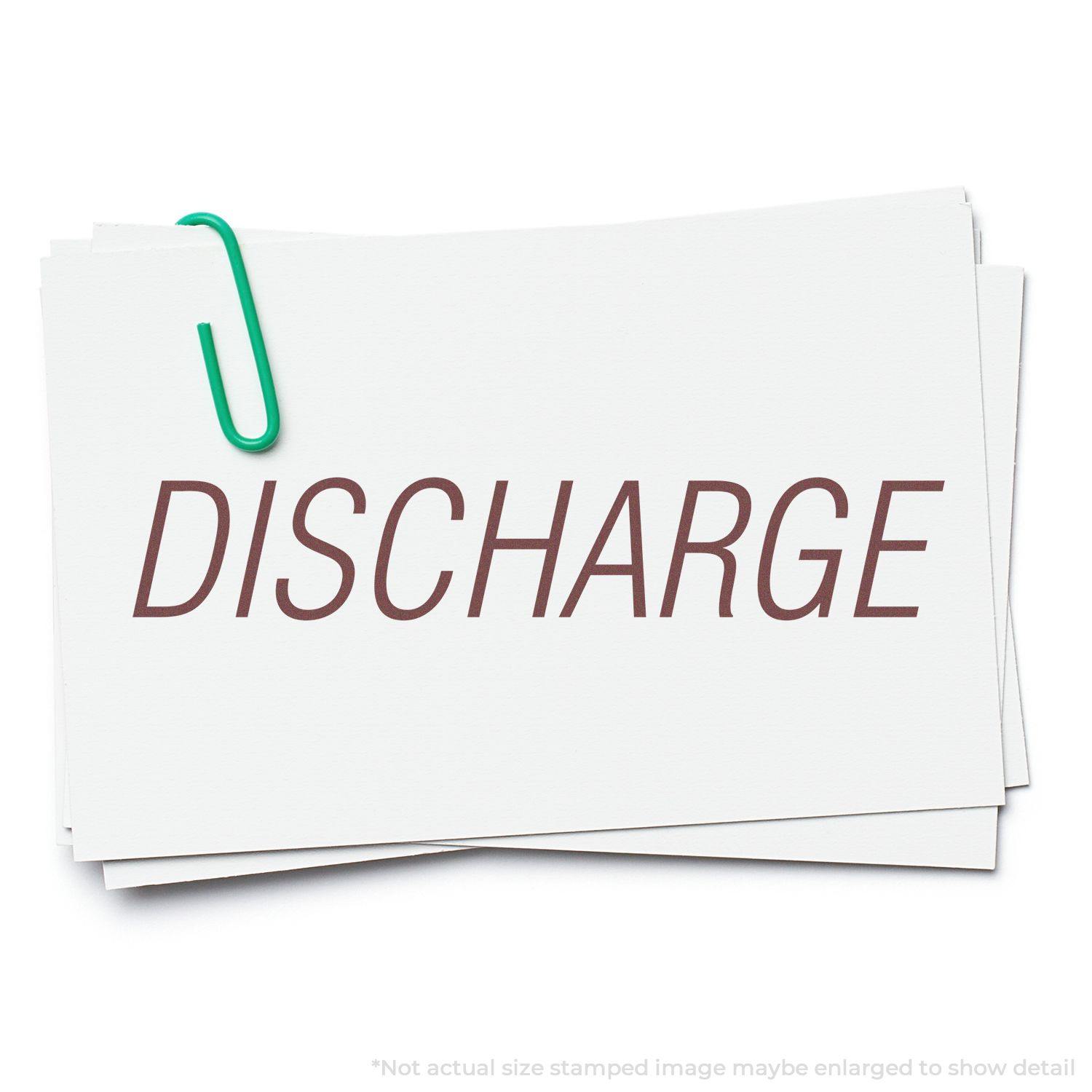 A stack of white cards with the word DISCHARGE stamped in brown ink using the Discharge Rubber Stamp, held together by a green paperclip.