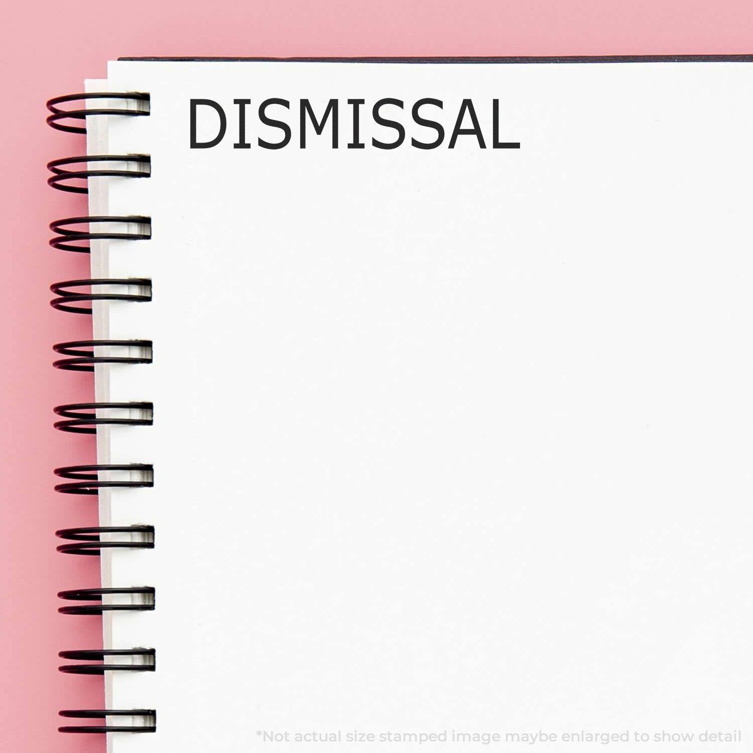 Dismissal Rubber Stamp imprint on a white spiral notebook with a pink background. The word DISMISSAL is clearly visible at the top of the page.