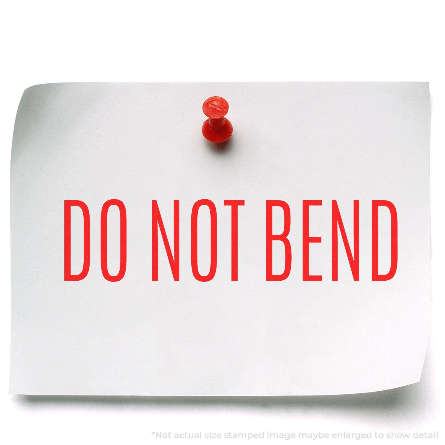 A white paper with DO NOT BEND in red, stamped using the Large Do Not Bend Rubber Stamp, pinned to a surface with a red pushpin.