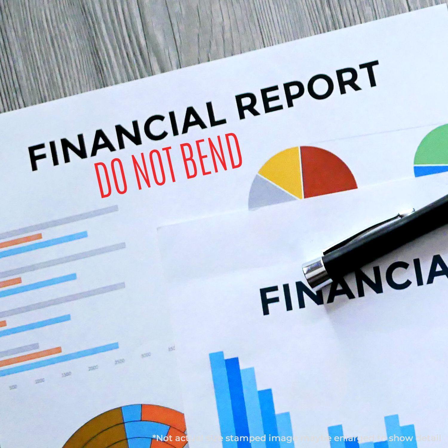 Self Inking Do Not Bend Stamp used on a financial report with charts and a pen on a wooden surface.