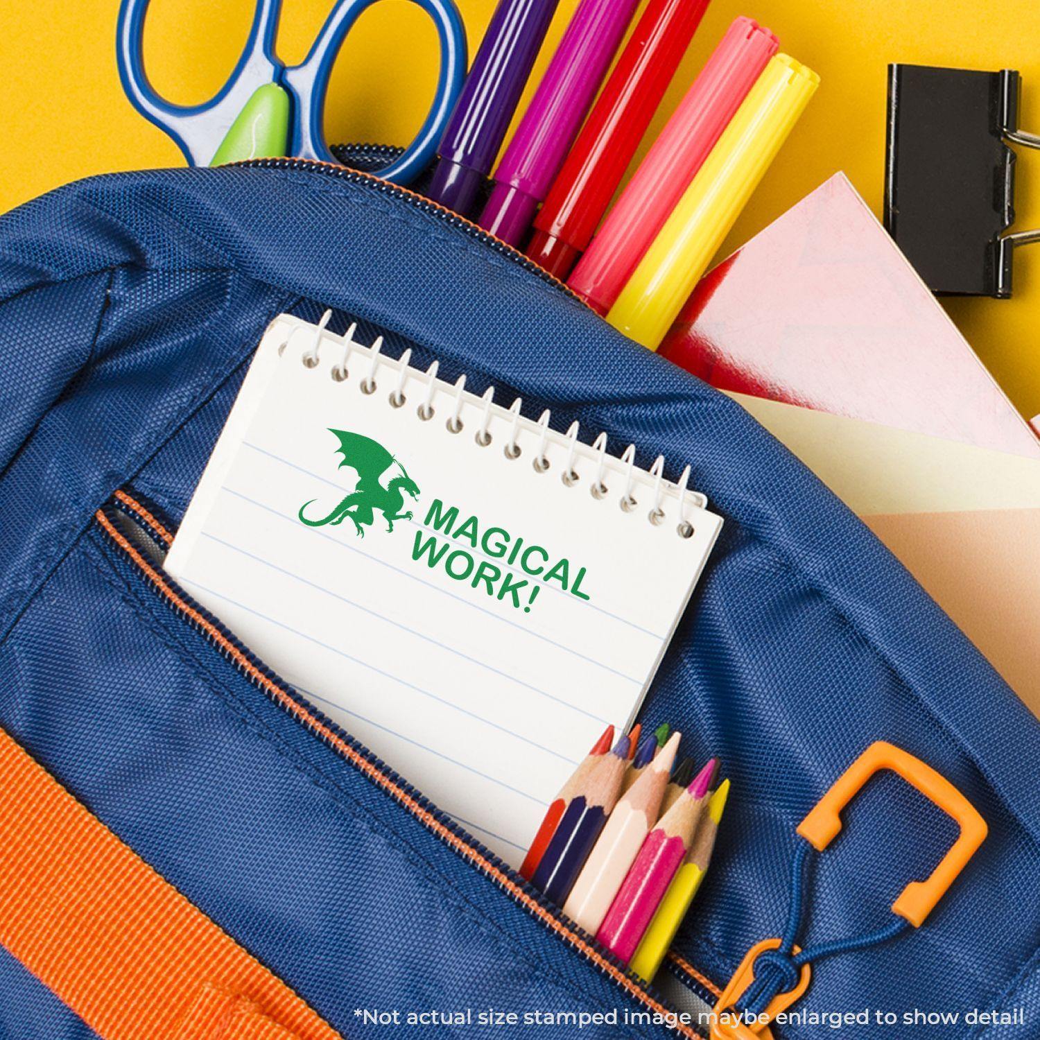 A Large Pre-Inked Dragon Magical Work Stamp imprint on a notepad, surrounded by colorful school supplies in a blue backpack.